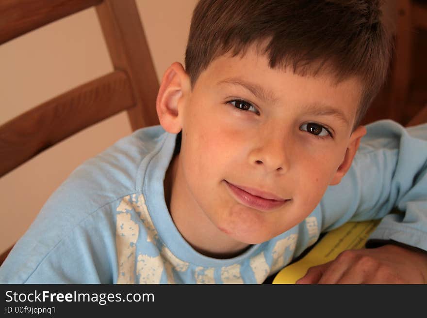 Schoolboy is reading and writing his school homework. Schoolboy is reading and writing his school homework