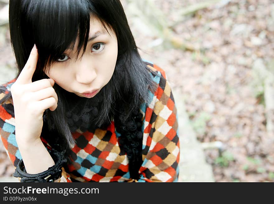 Asian girl in stripes looking at viewer with a finger on her head. Asian girl in stripes looking at viewer with a finger on her head