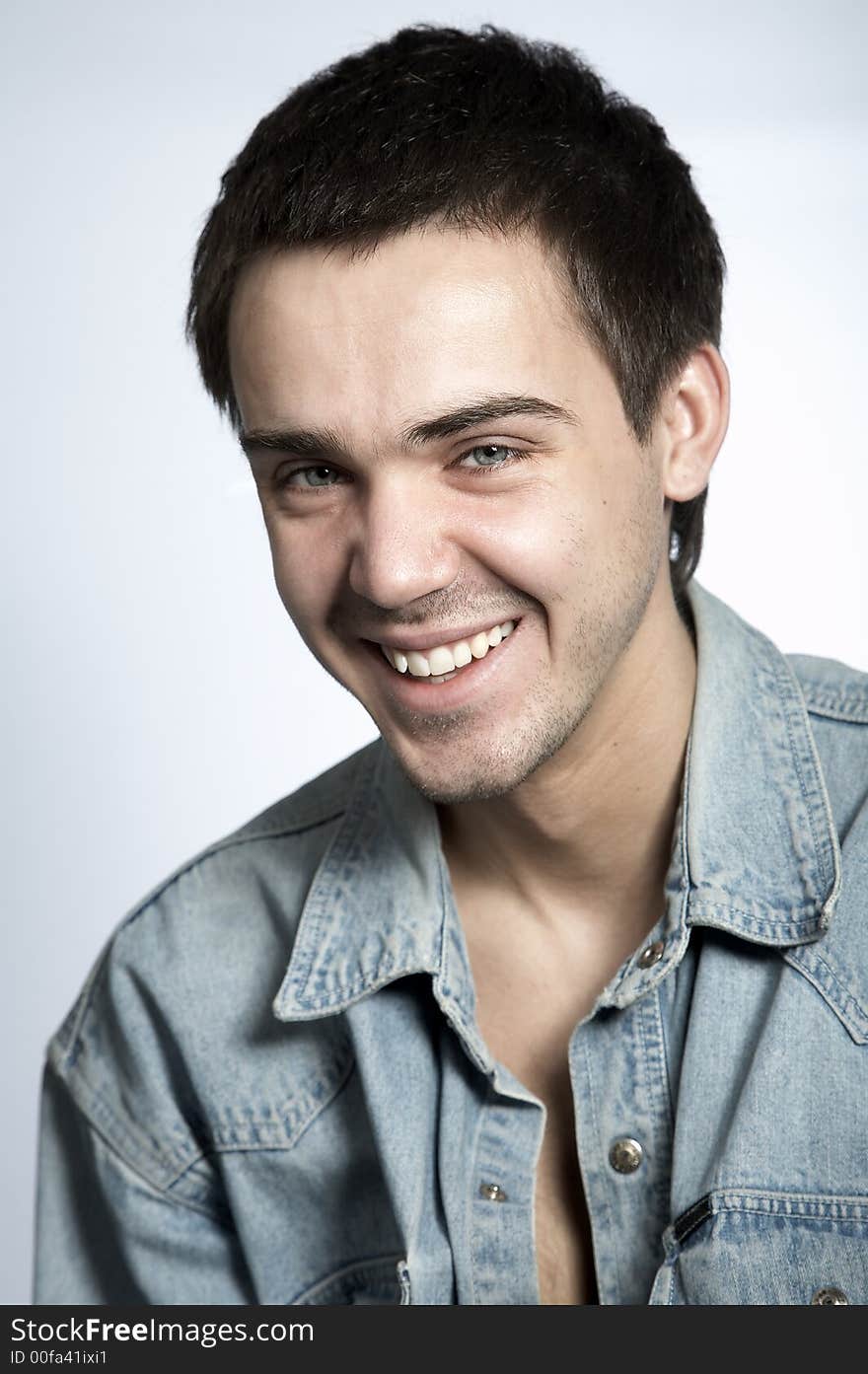 Smiling attractive yyoung man in blue jeans shirt on white background. Smiling attractive yyoung man in blue jeans shirt on white background