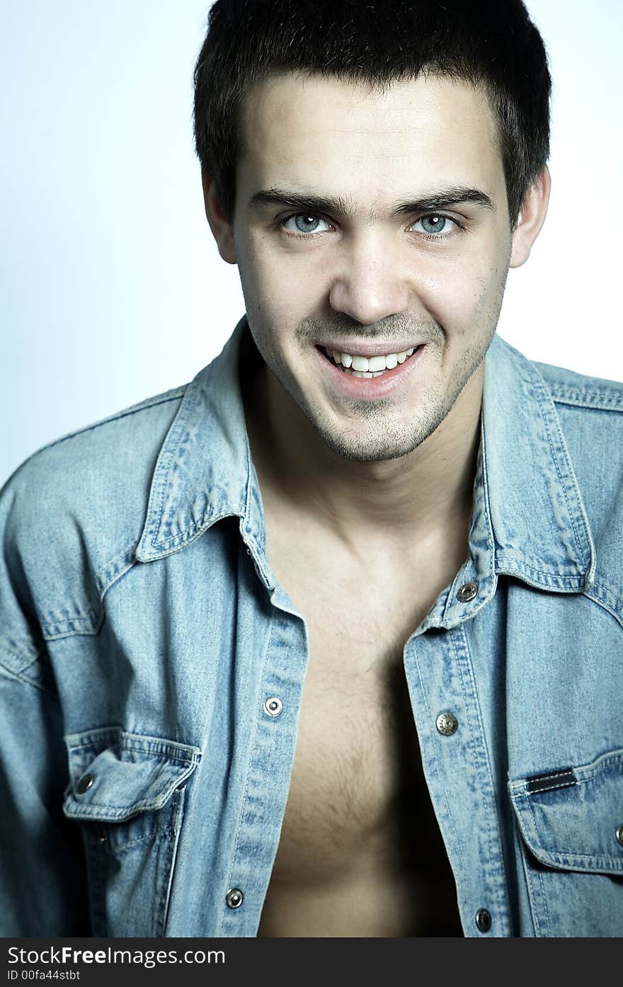 Smiling attractive yyoung man in blue jeans shirt on white background. Smiling attractive yyoung man in blue jeans shirt on white background