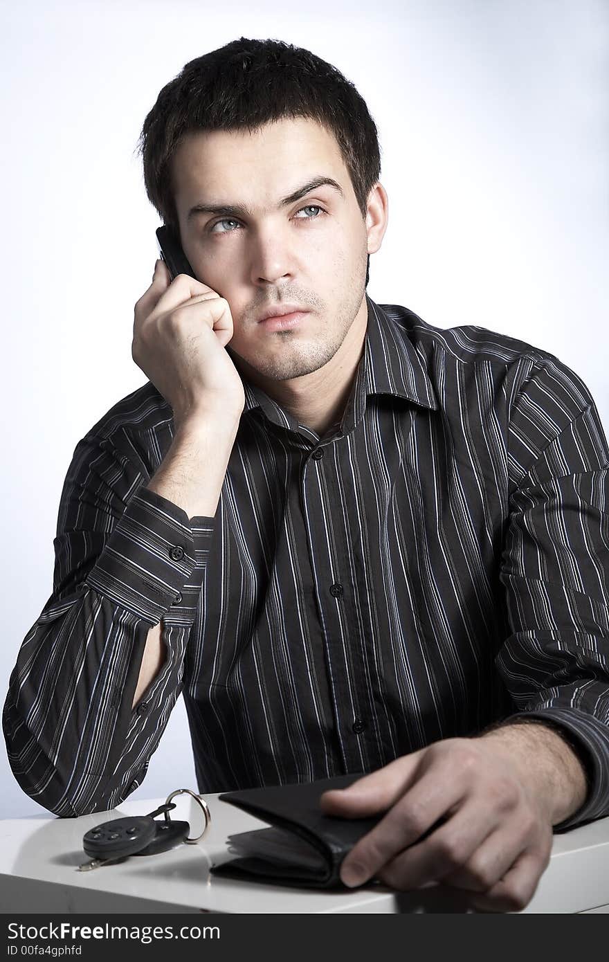 Serious young man with car keys and wallet speaking phone. Serious young man with car keys and wallet speaking phone