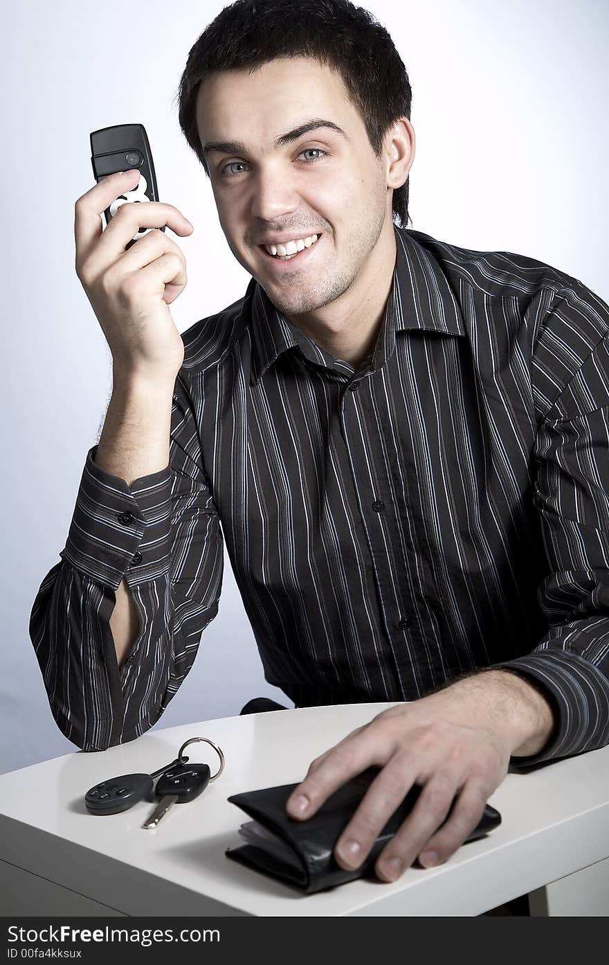 Smiling young man with car keys and wallet speaking phone. Smiling young man with car keys and wallet speaking phone