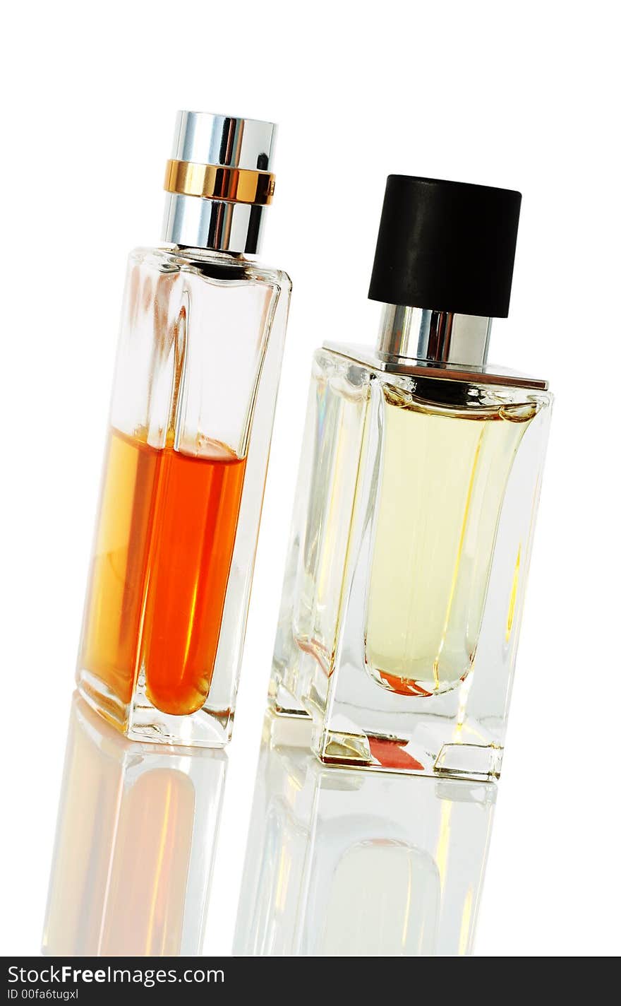 Two elegant perfume bottles standing on reflective surface.