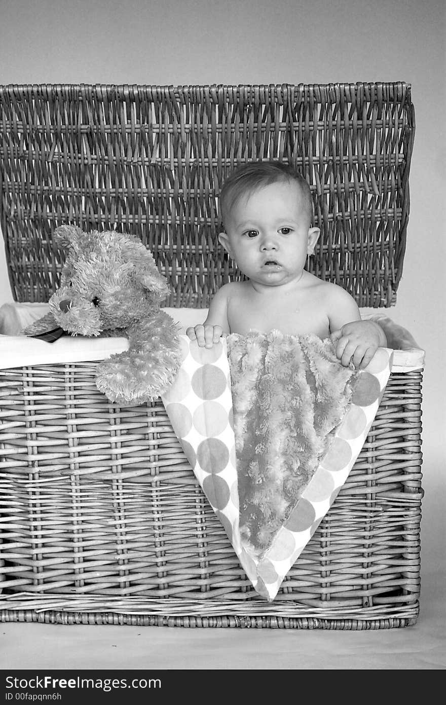 Image of cute baby and teddy bear peeking out of a wicker trunk