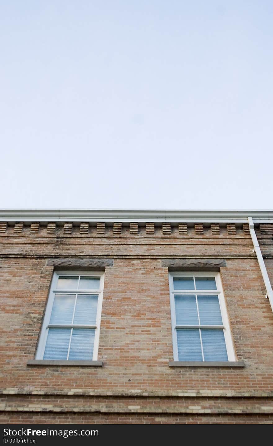 Two vertical windows on a brick building with blue sky and copy space. Two vertical windows on a brick building with blue sky and copy space.