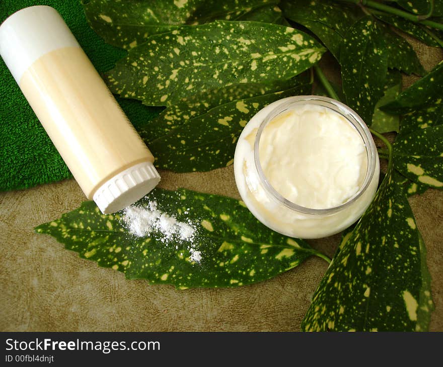 Cream, bottle og powder and towel with green leaves. Cream, bottle og powder and towel with green leaves