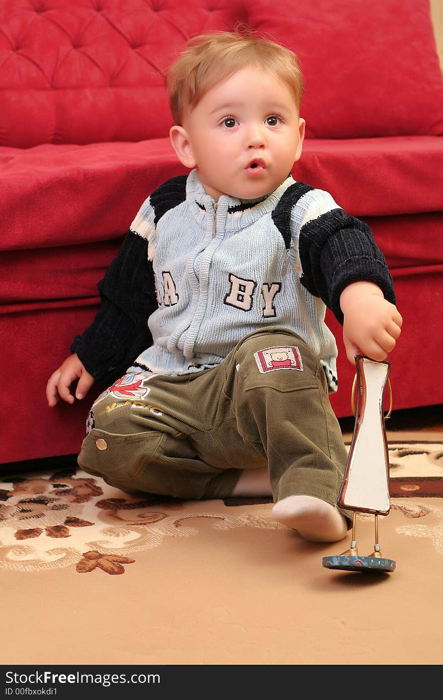 Little blond baby boy surprised playing with toys at home