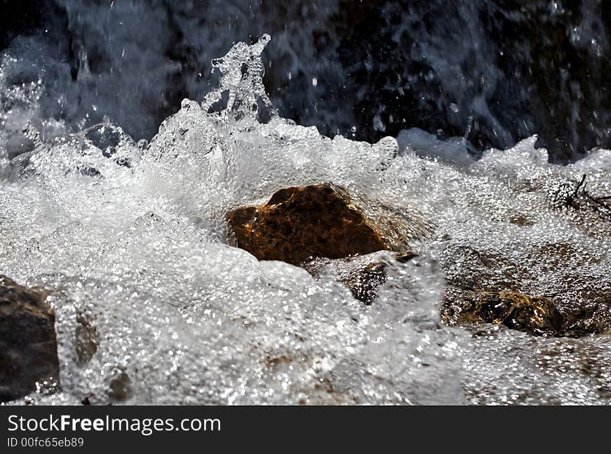 Water flowing beneath rocks at mountain waterfall