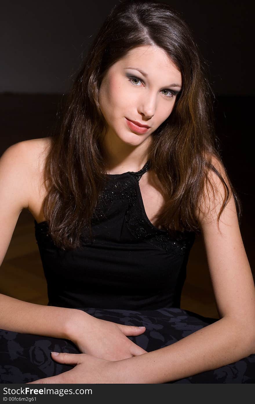 Beautiful young woman in black shirt in front of a black background. Beautiful young woman in black shirt in front of a black background