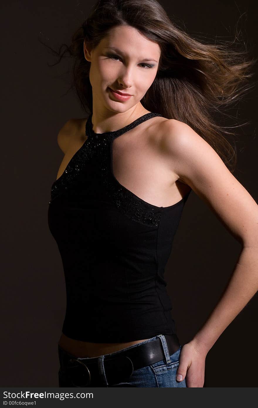 Beautiful young woman in black shirt in front of a black background. Beautiful young woman in black shirt in front of a black background