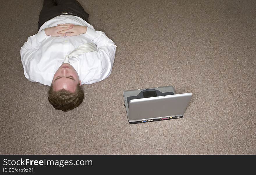 Businessman lying on the floor next to his computer laptop. Businessman lying on the floor next to his computer laptop