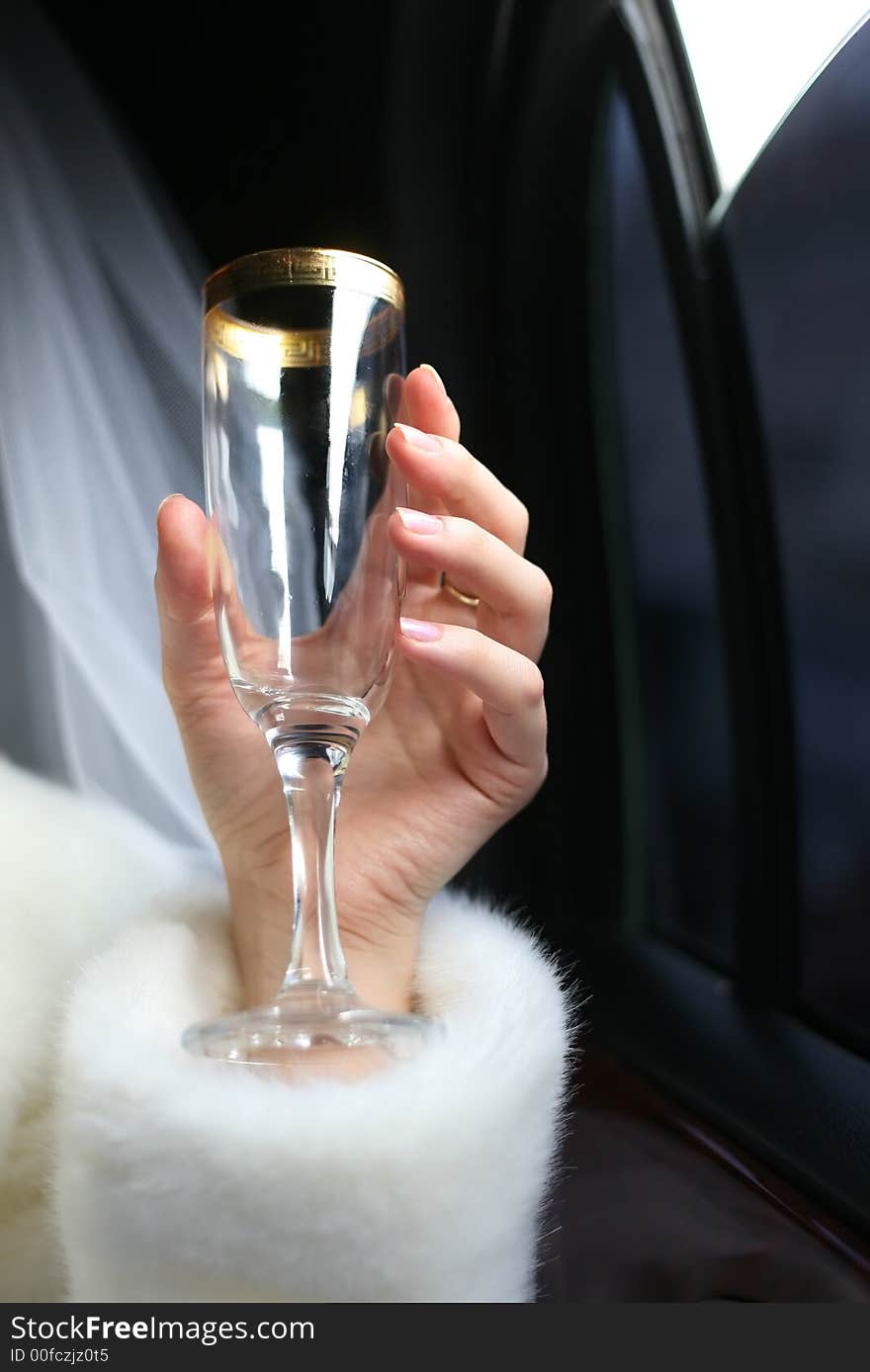 Glass with champagne in a hand of the bride