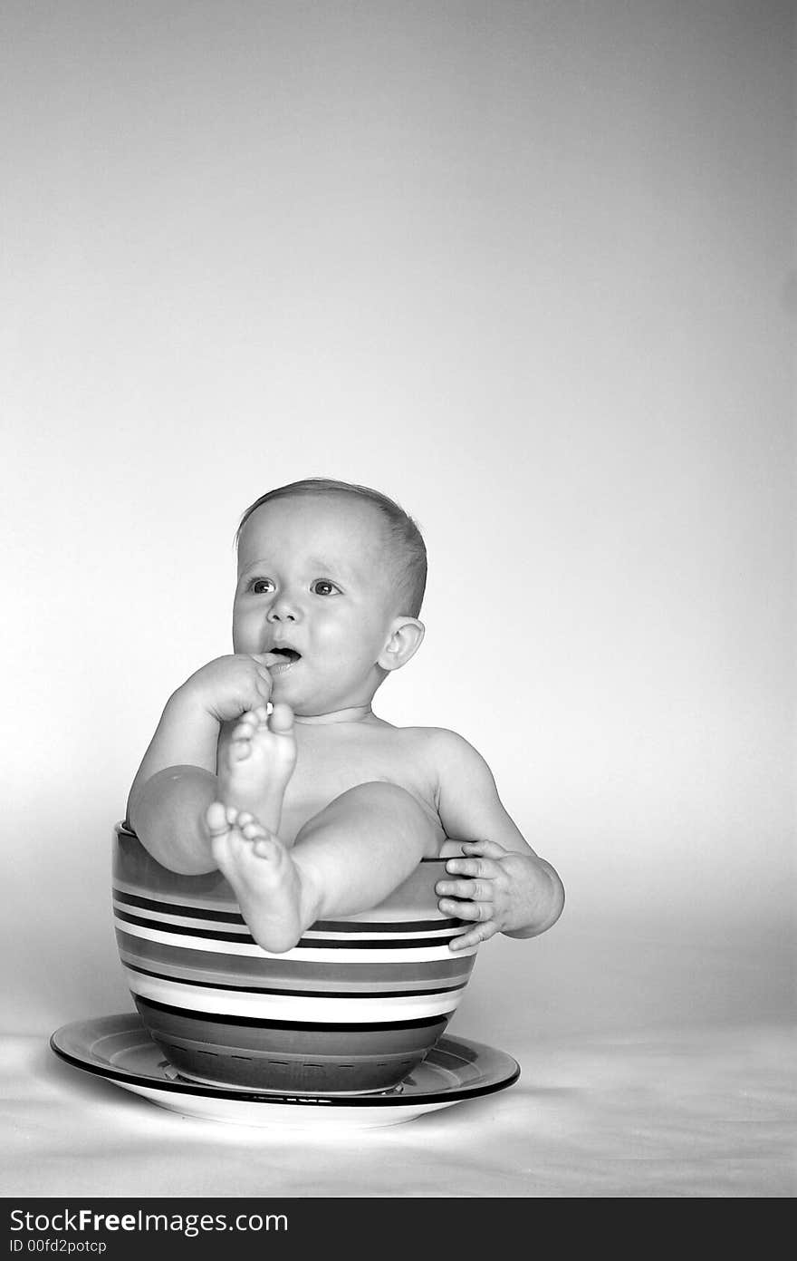 Black and white image of an adorable baby sitting in a colorful, over-sized teacup. Black and white image of an adorable baby sitting in a colorful, over-sized teacup