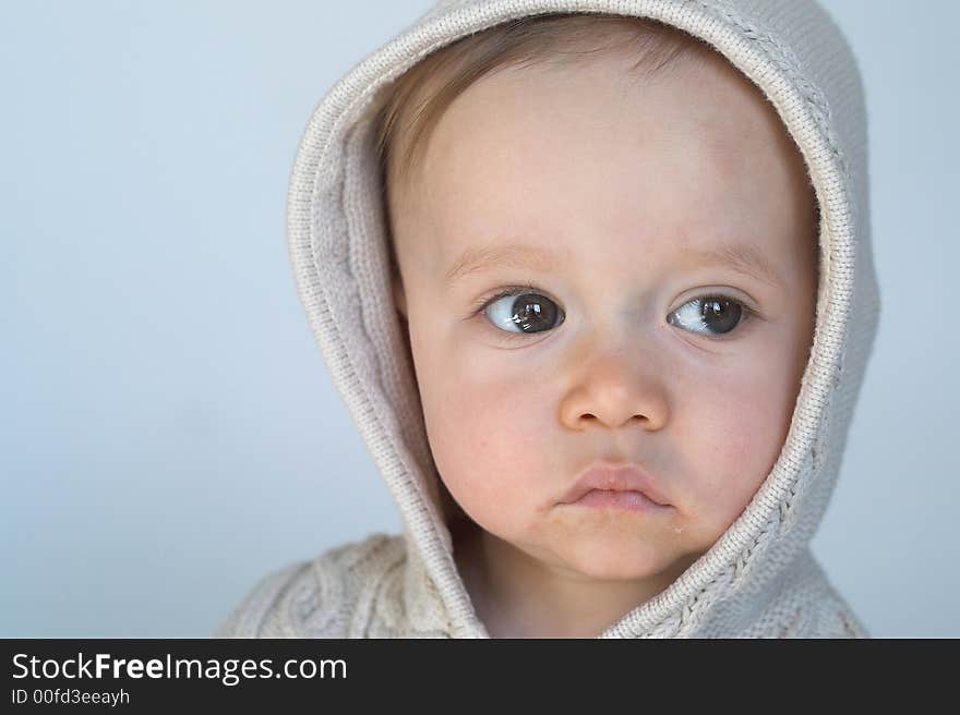 Image of cute baby wearing a hooded sweater, sitting in front of a white background. Image of cute baby wearing a hooded sweater, sitting in front of a white background