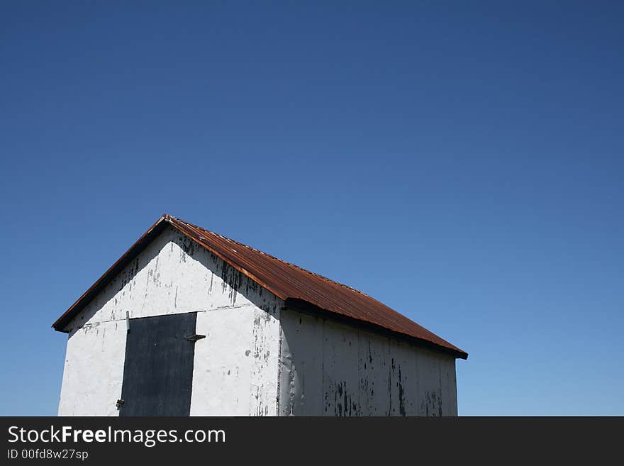 White rural hut and spacious blue sky (barn on the farm). White rural hut and spacious blue sky (barn on the farm).