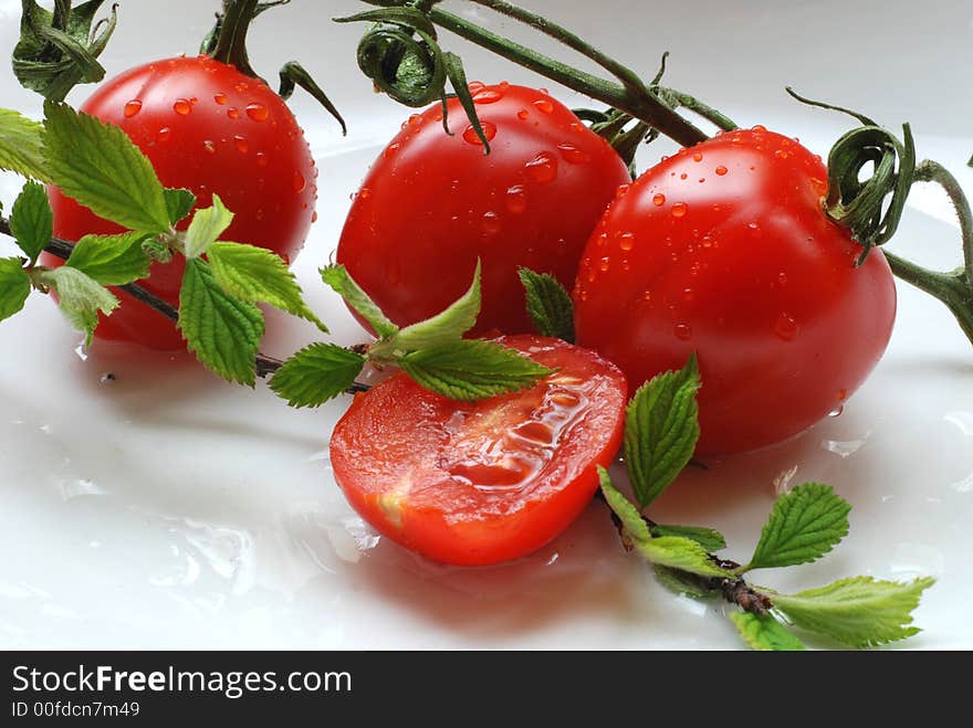 Tomatoes with water drops on them and green branch. Tomatoes with water drops on them and green branch