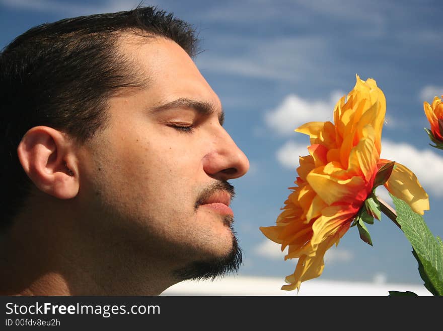 Young man with a flower on the blue sky background. Young man with a flower on the blue sky background