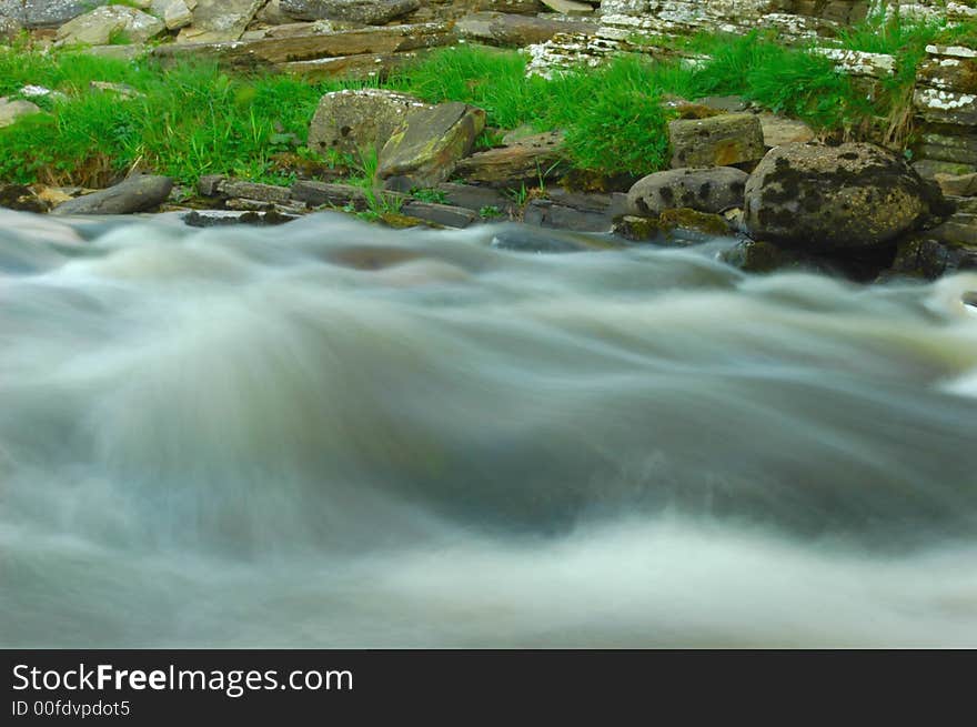 A river rushing past on its way to the sea bubbling over submerged rocks.