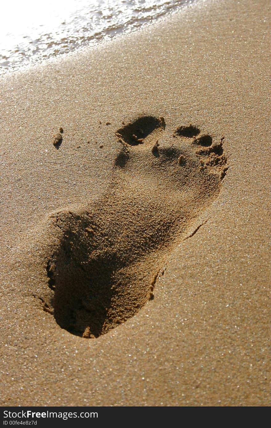 Footprint at a beautiful beach right before a wave advances to wash it away. Footprint at a beautiful beach right before a wave advances to wash it away