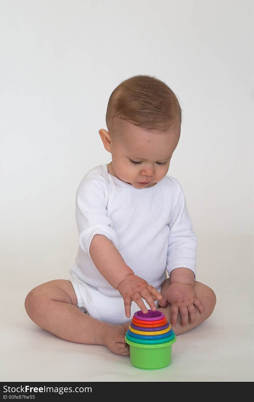 Image of an adorable baby playing with colorful stacking cups. Image of an adorable baby playing with colorful stacking cups