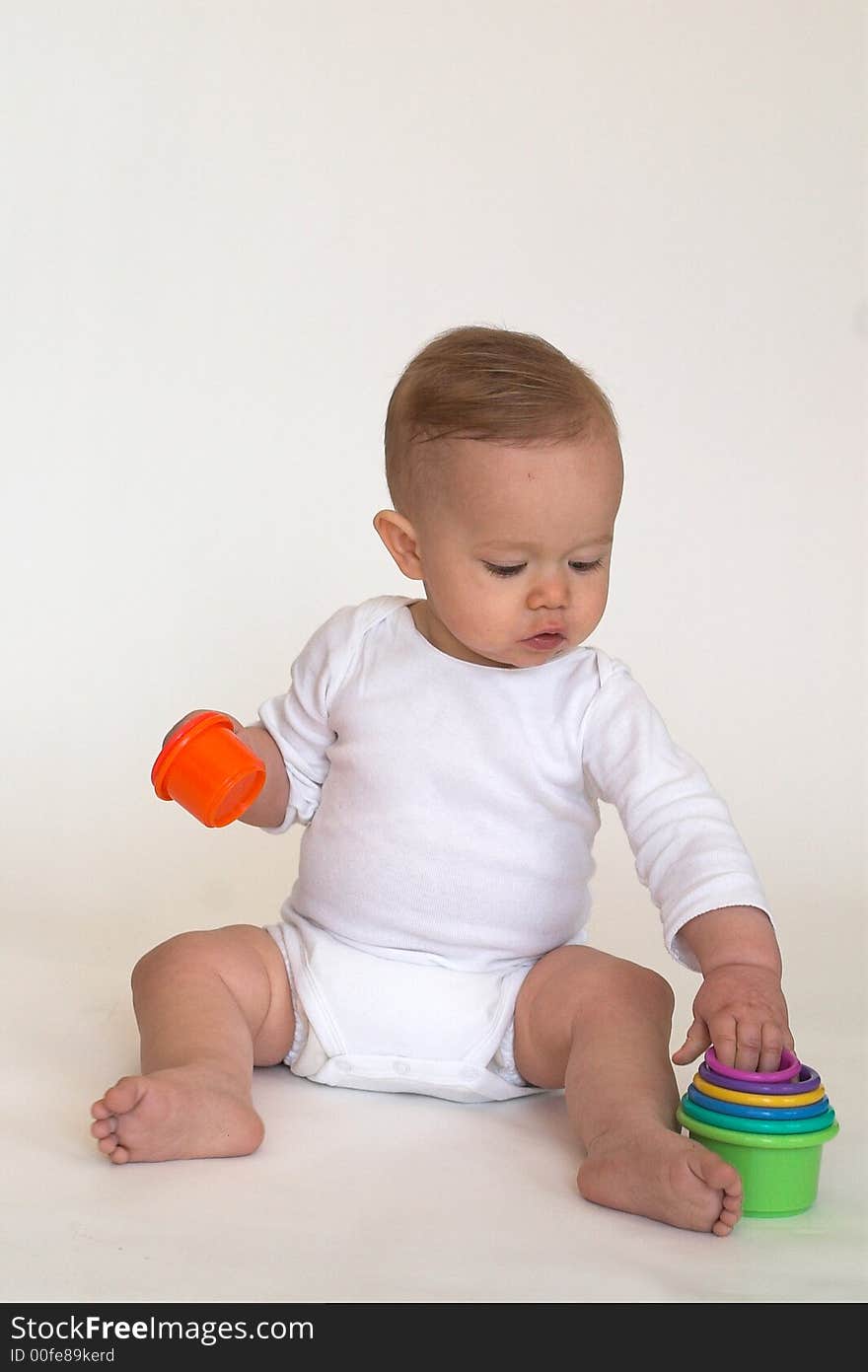 Image of an adorable baby playing with colorful stacking cups. Image of an adorable baby playing with colorful stacking cups