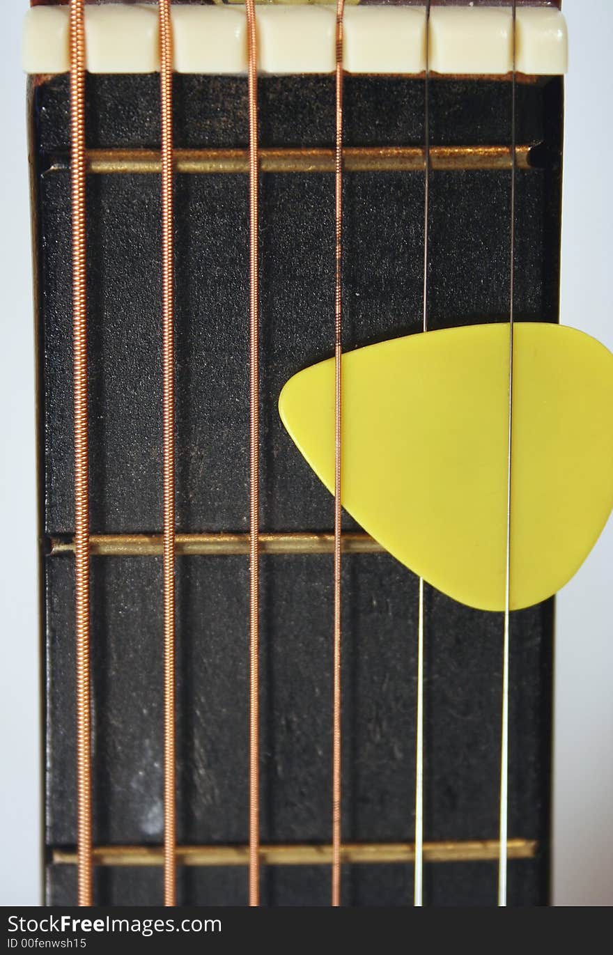 An image of a Acoustic Guitar Neck with Yellow Pick