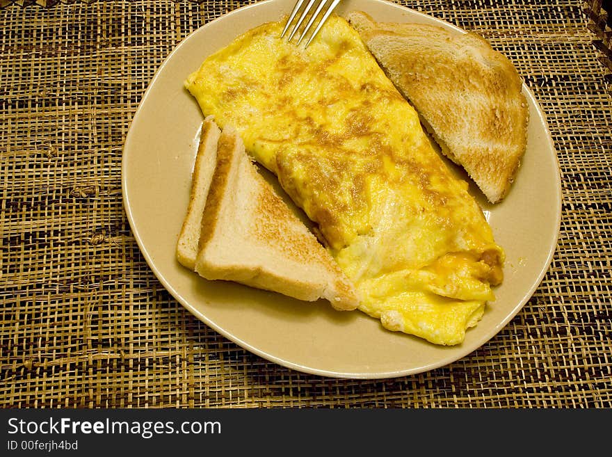 Omelette and white toast on a tan plate on a wicker placemat. Omelette and white toast on a tan plate on a wicker placemat