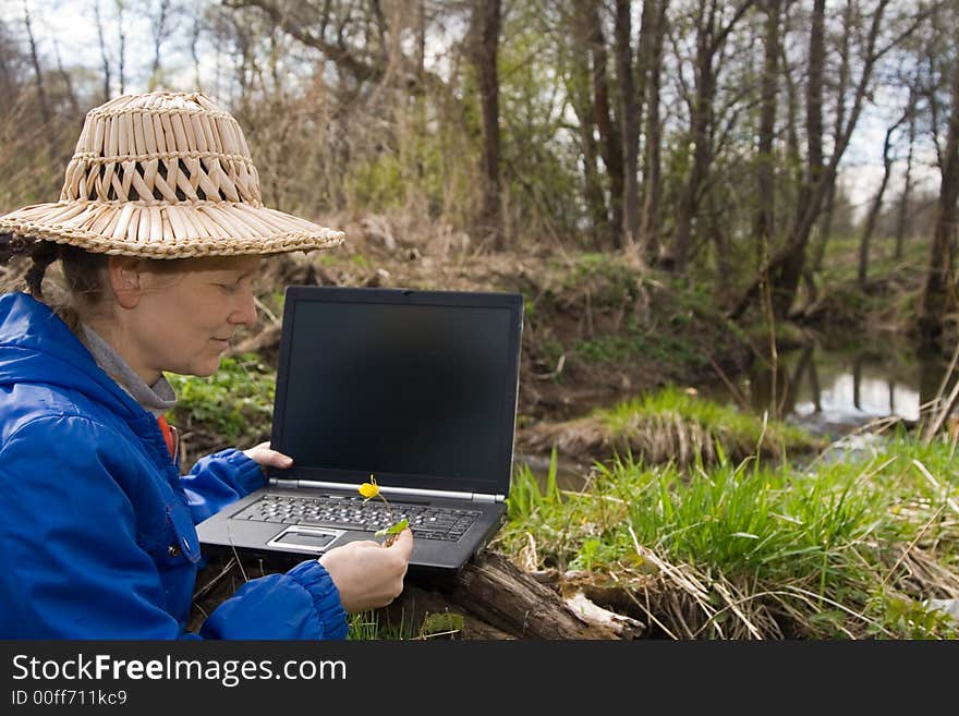 Woman in straw hat with notebook smiling and looking at yellow flower. Woman in straw hat with notebook smiling and looking at yellow flower.