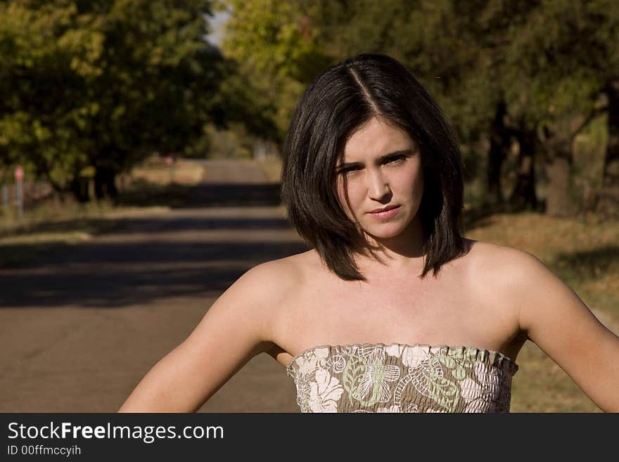 Closeup of beautiful and sexy brunette looking at the camera with a tree lane behind her. Closeup of beautiful and sexy brunette looking at the camera with a tree lane behind her