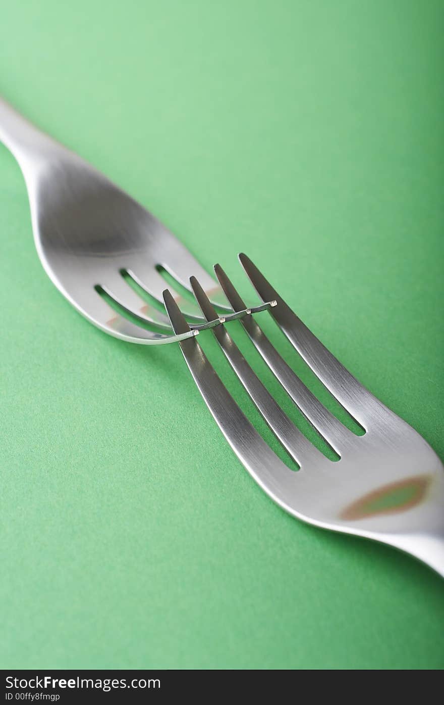 Two forks crossed on the green table