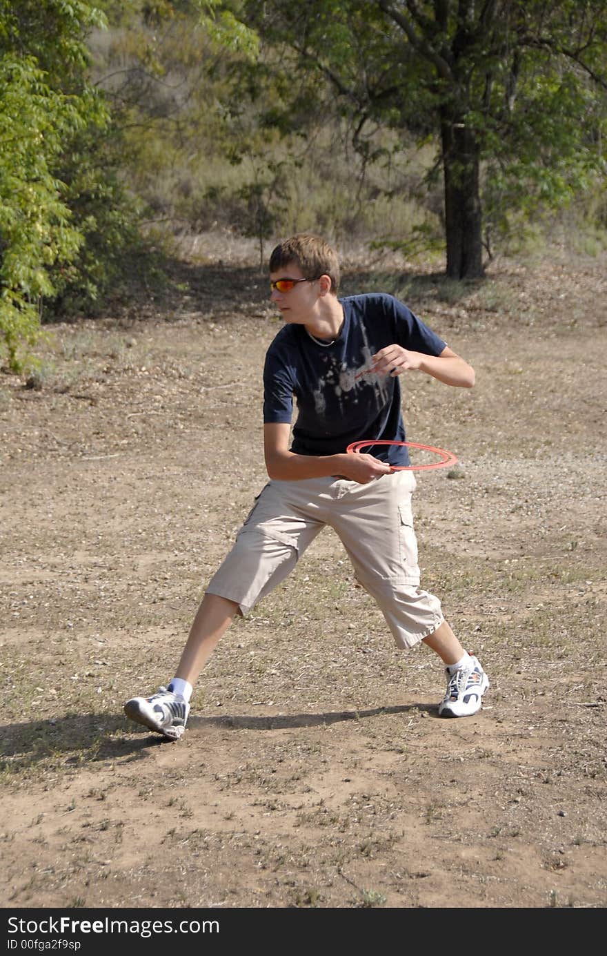 Activities in the park. A teenage bot is passing a ring.