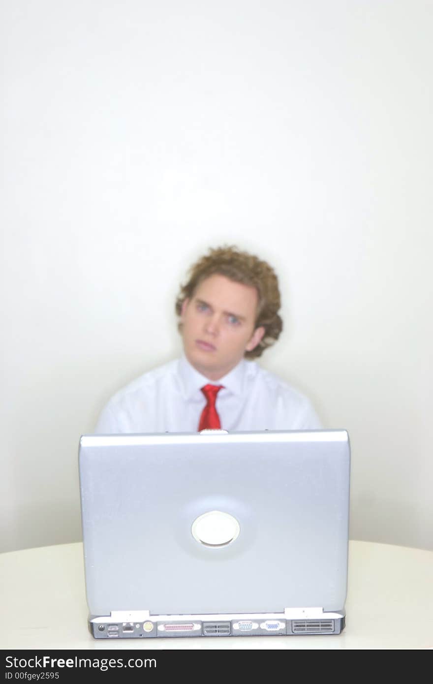 Businessman sitting behind his laptop with an inquisitive and puzzling look. Businessman sitting behind his laptop with an inquisitive and puzzling look