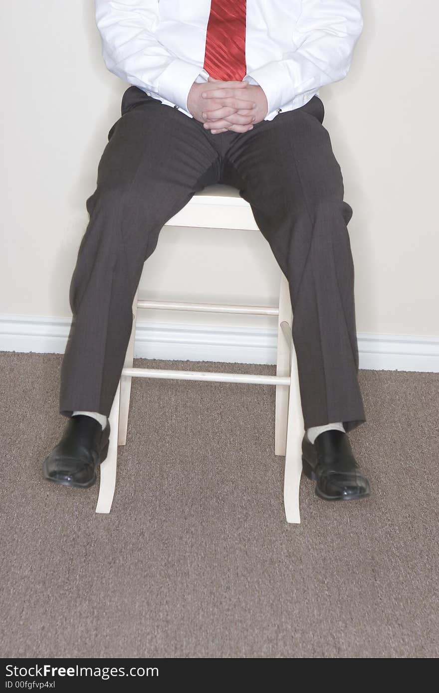 Businessman sitting on a high chair dangling his feet off the chair. Businessman sitting on a high chair dangling his feet off the chair