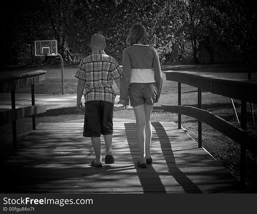 Brother & sister holding hands while crossing the bridge.

Black & White