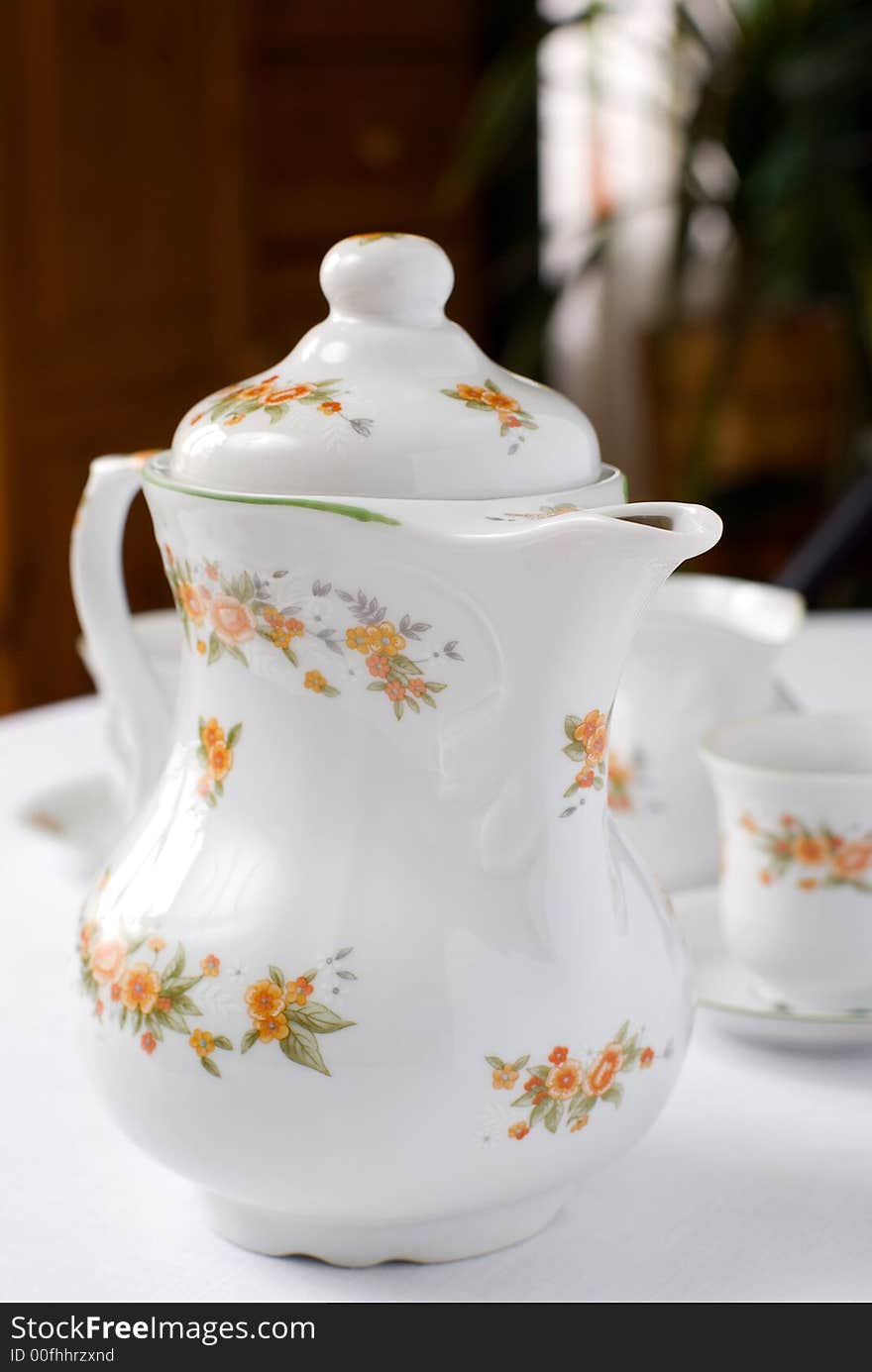 Coffee or tea set on the table - teapot on the front (focus on it) cups and milk jug behind. Shallow DOF. Coffee or tea set on the table - teapot on the front (focus on it) cups and milk jug behind. Shallow DOF.