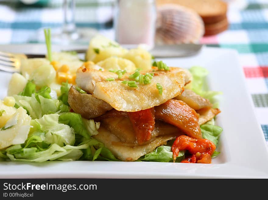 Grilled hake filet with roast pepper and aubergine on lettuce and potato salad. Grilled hake filet with roast pepper and aubergine on lettuce and potato salad