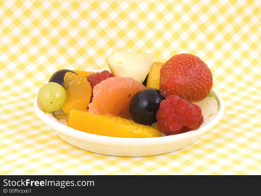 Fruit-salad on a plate with yellow-white background