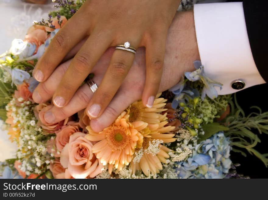 Bride and groom's hands over wedding bouquet. Bride and groom's hands over wedding bouquet