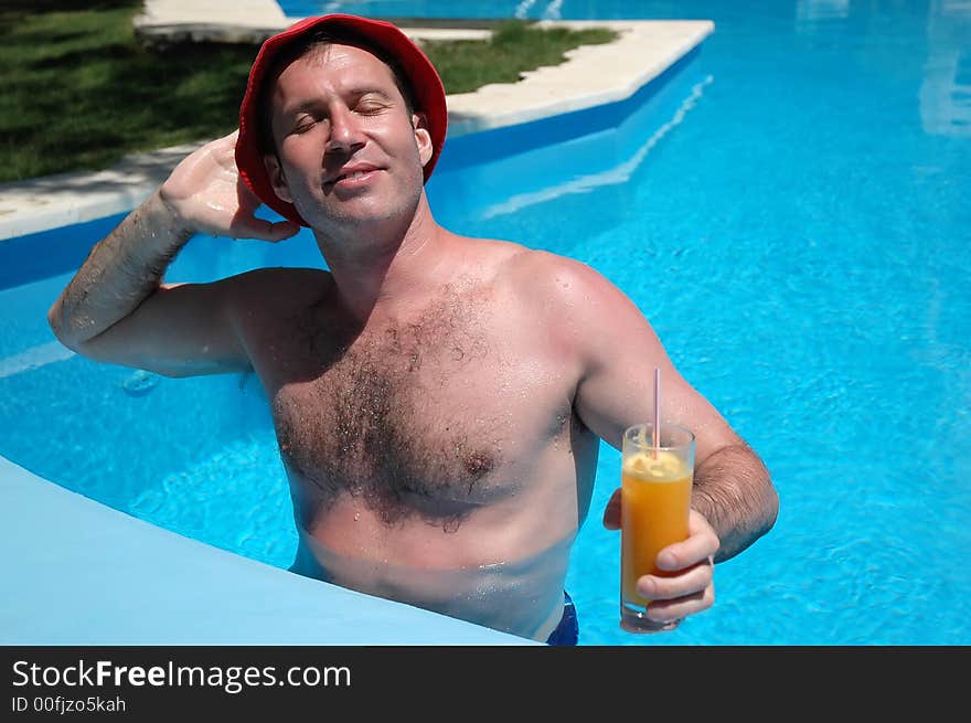 Man with drink in the pool enjoying sunlight. Man with drink in the pool enjoying sunlight