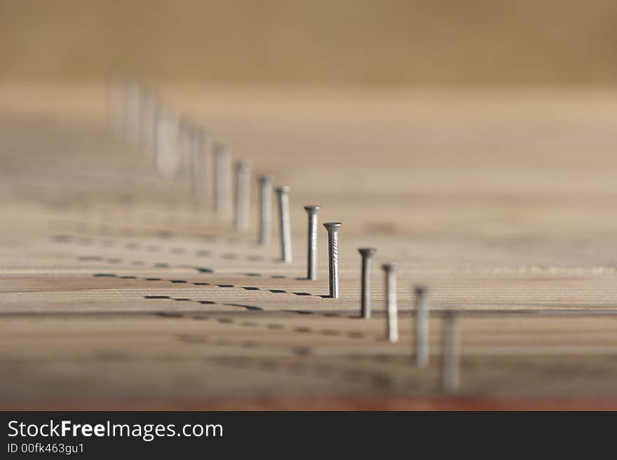 Line of nails in timber decking, only one nail in focus, very shallow depth of field.