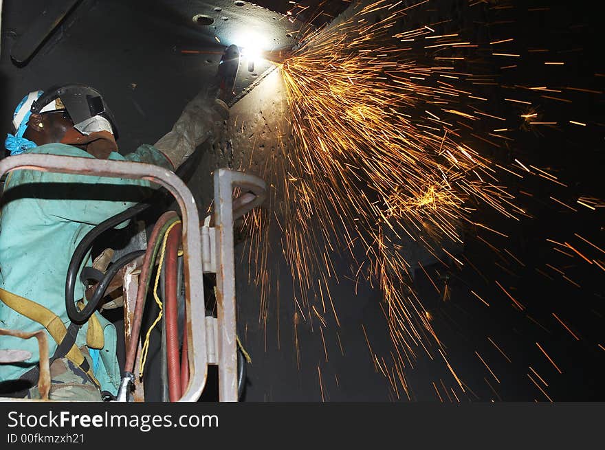 Arc welder under ship in basket working. Arc welder under ship in basket working