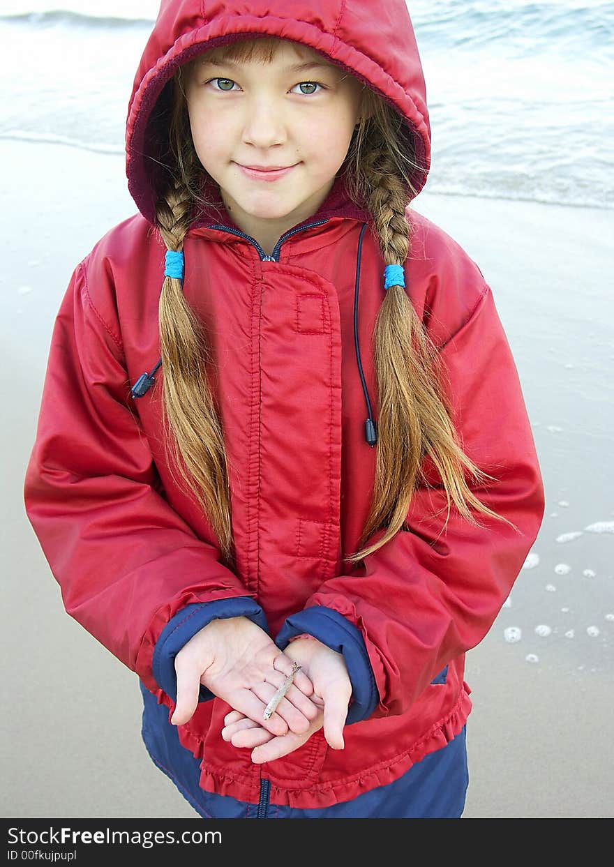 The girl holds a small fish in hands. The girl holds a small fish in hands