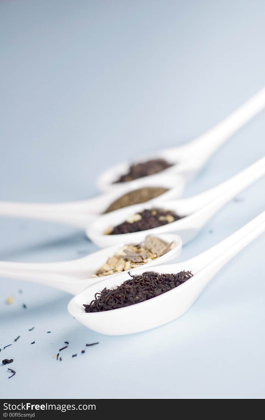 Four spoons with tea on blue background