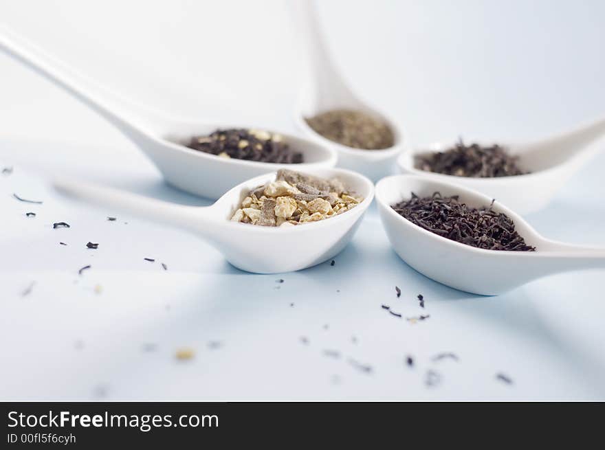 Four spoons with tea on blue background