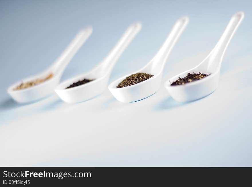 Four spoons with tea on blue background