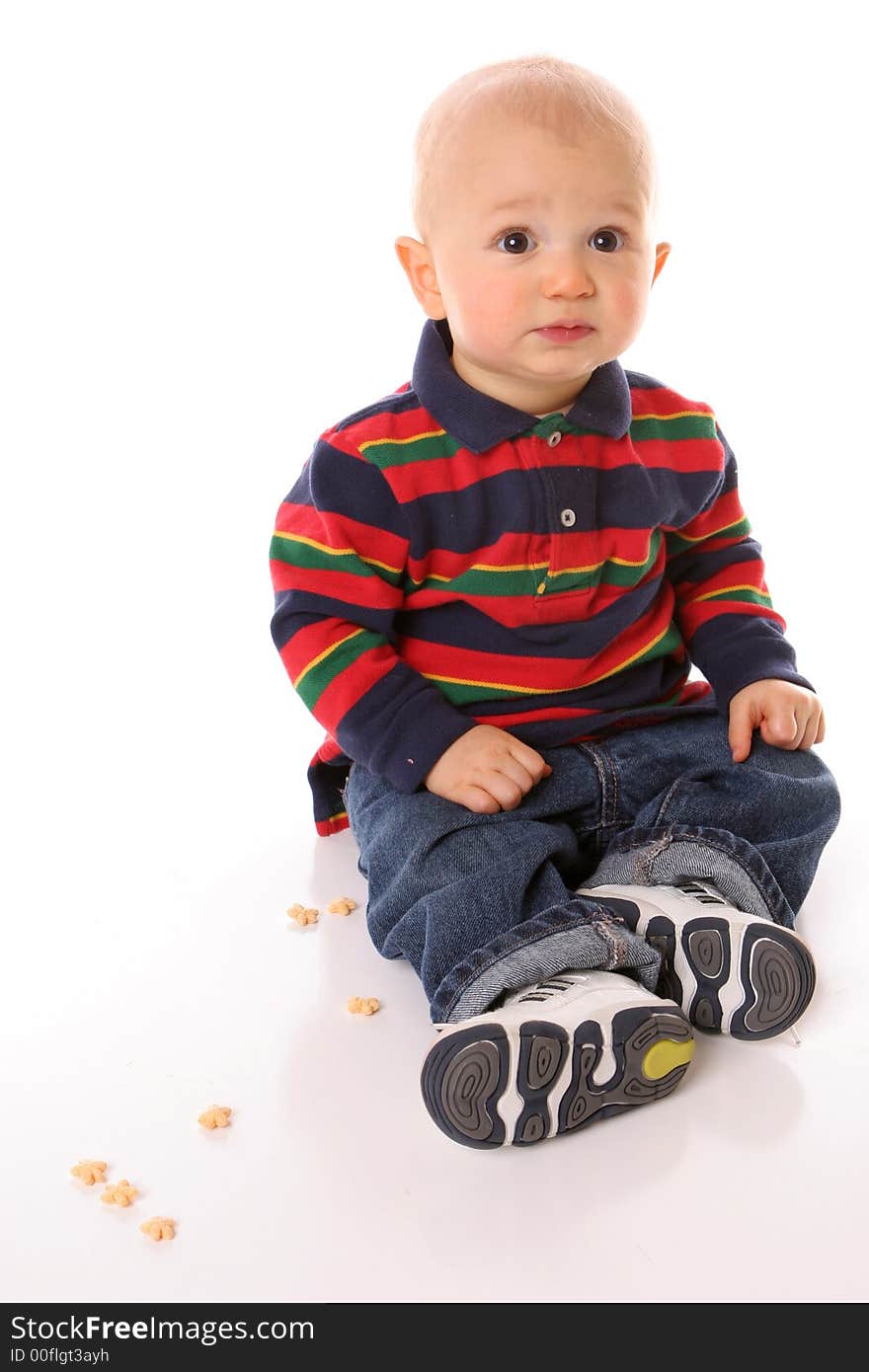 Toddler sitting with snacks around him. Toddler sitting with snacks around him