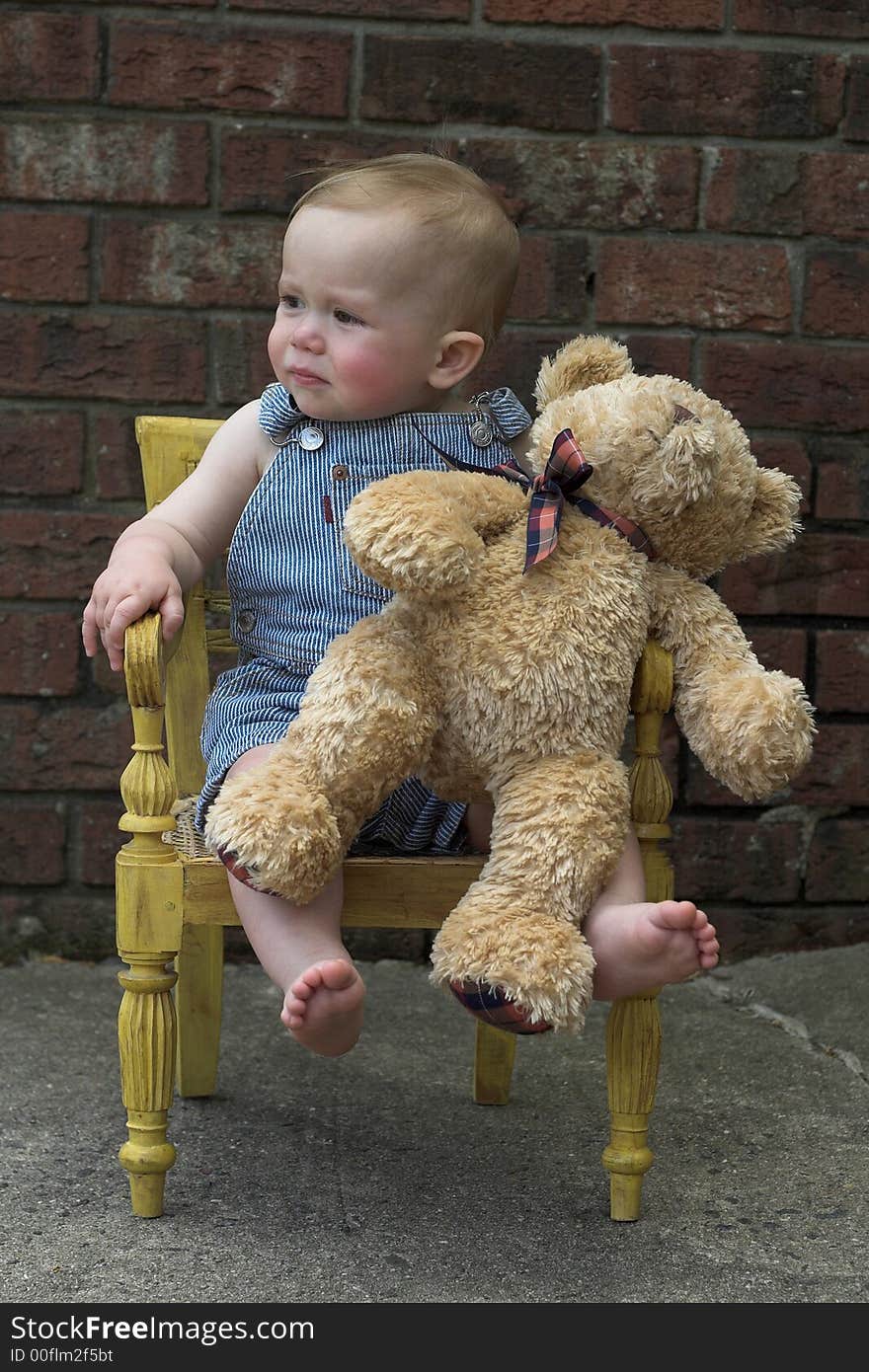 Image of cute toddler and teddy bear sitting in a chair