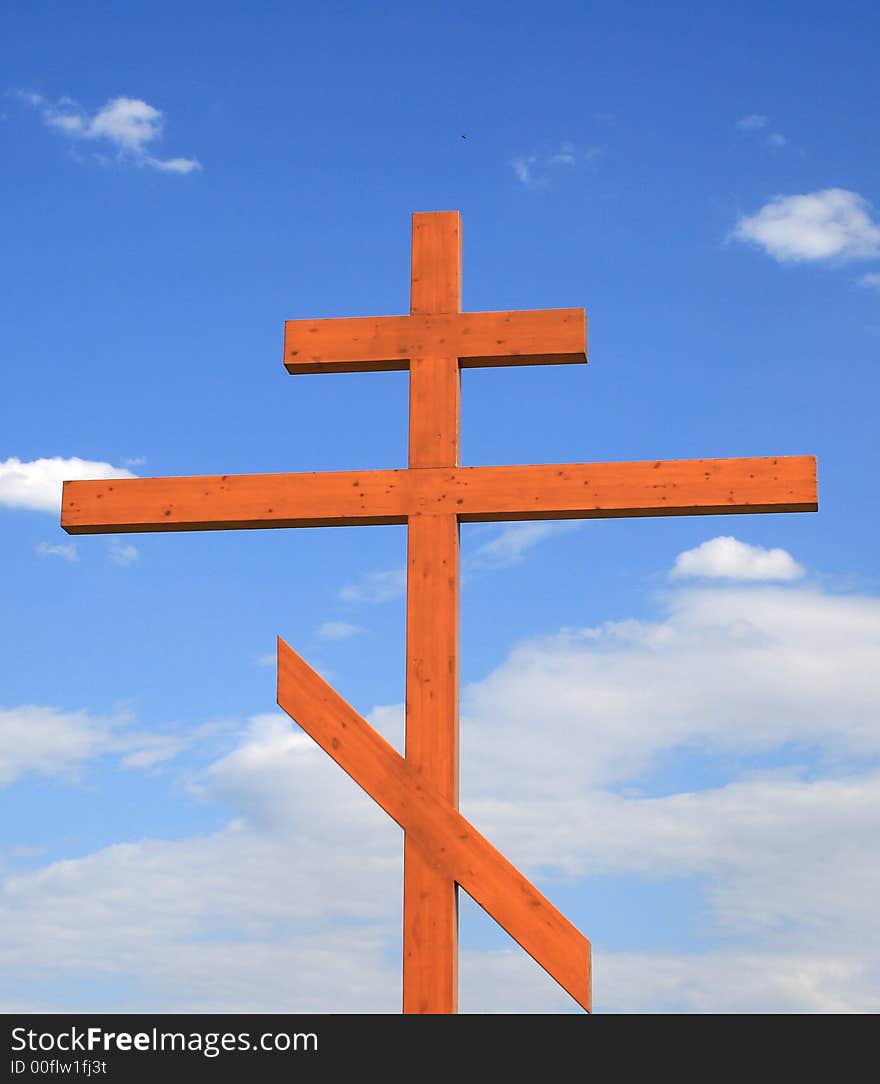 Wooden cross on a background of the blue sky with clouds