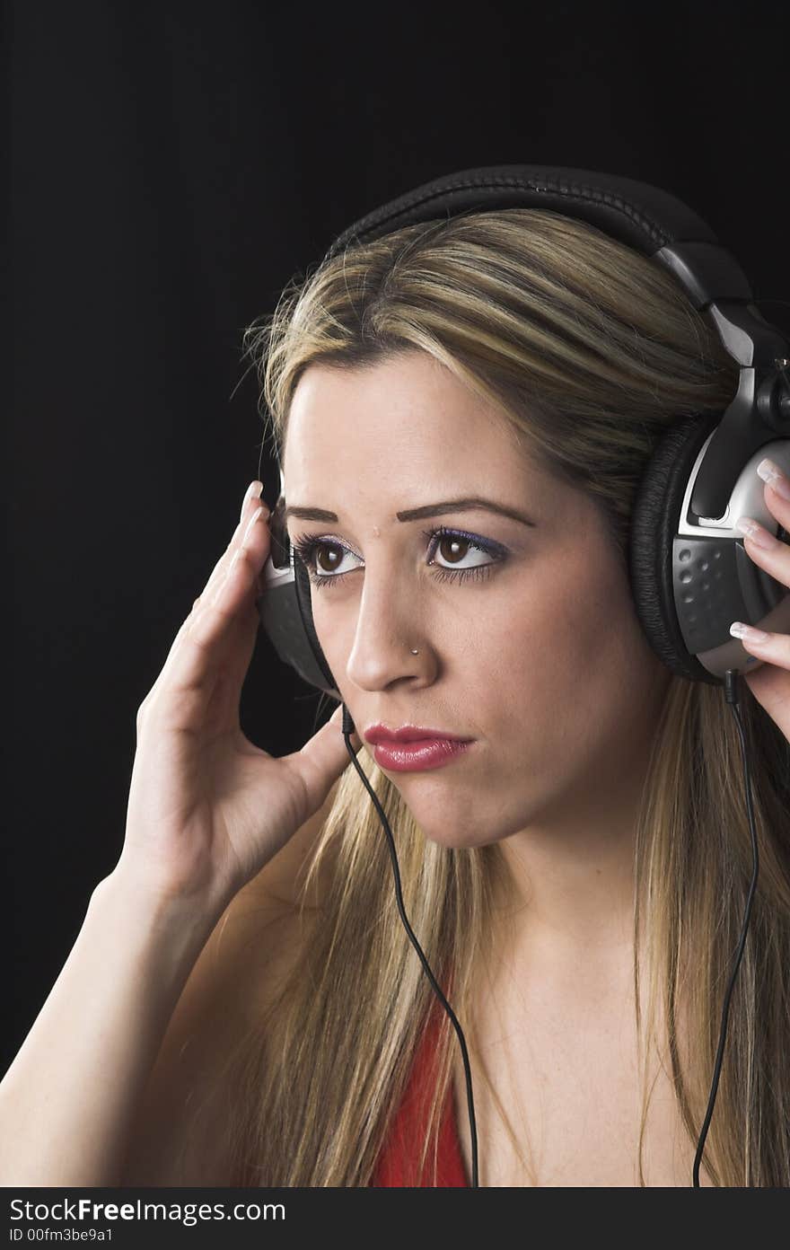 Fashion portrait of young woman  listening to music over black background