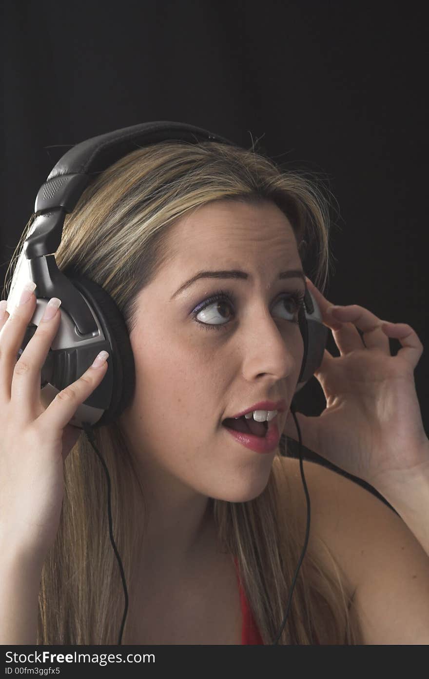 Fashion portrait of young woman listening to music over black background. Fashion portrait of young woman listening to music over black background